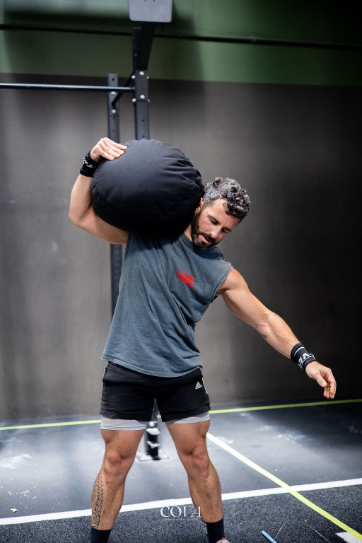 Un adhérent porte un sandbag sur l’épaule pendant une série.